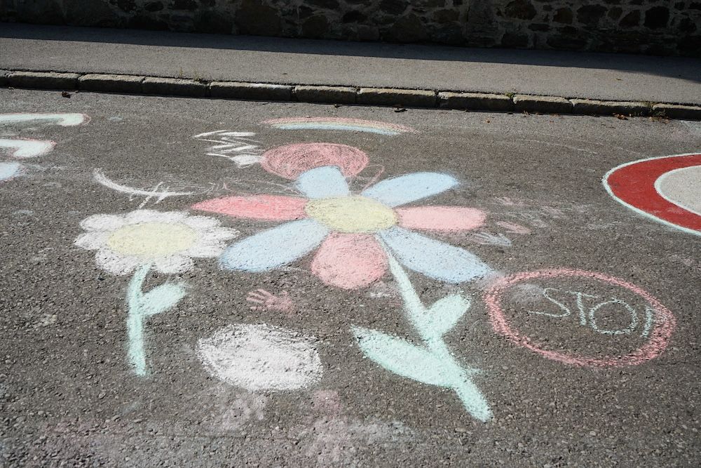 Die Straße ist mit bunten Kreideblumen und einem "STOP"-Zeichen bemalt. Kreatives Straßenkunstwerk.